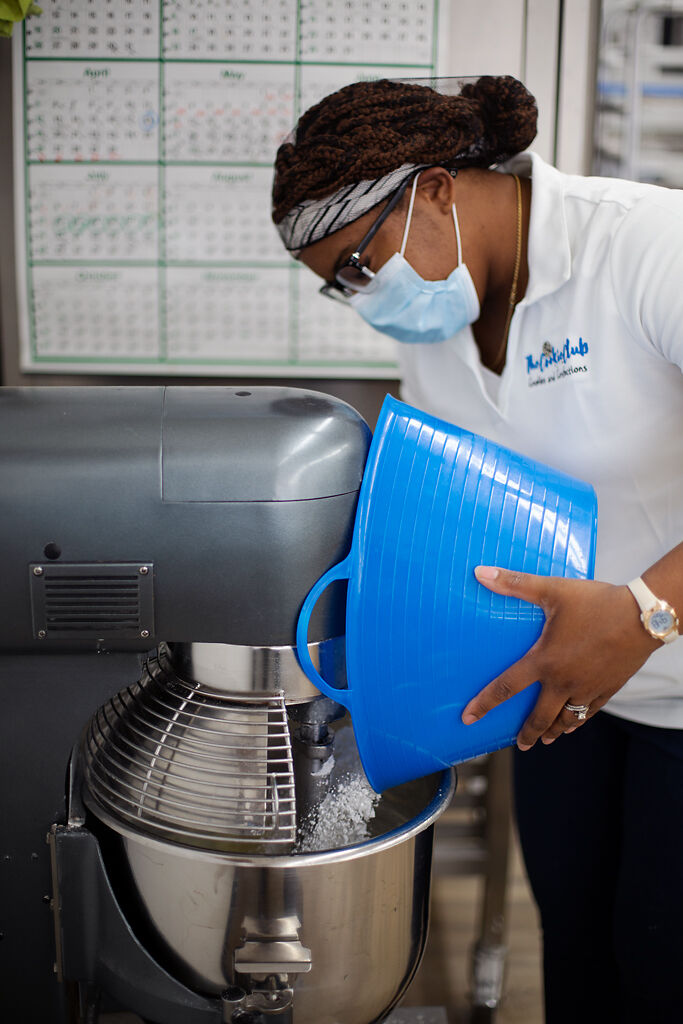 Kiarah Harris pours powdered sugar into a mixer while making homemade buttrecream icing